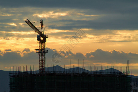 穿透云层光日出时的建筑工地塔吊背景