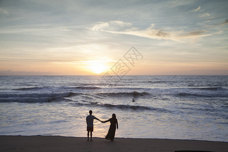 走在沙滩上情侣在夕阳西下的海边看大海背景