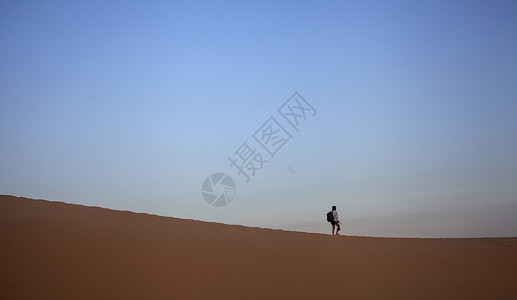 旅行中一个人孤独的在沙漠上行走背景图片