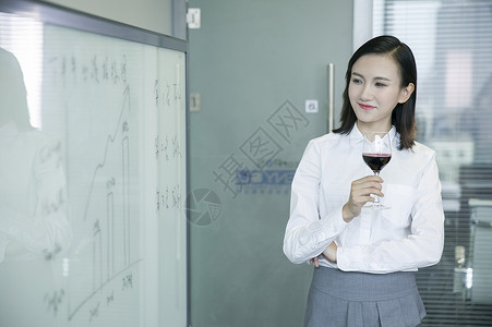 商务女士手举红酒看着会议板上数据背景图片