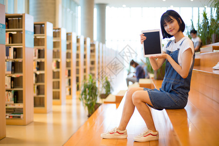 学习阶梯坐在图书馆使用平板的女生背景