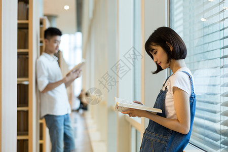 毕业情侣一起在图书馆看书的男生女生背景