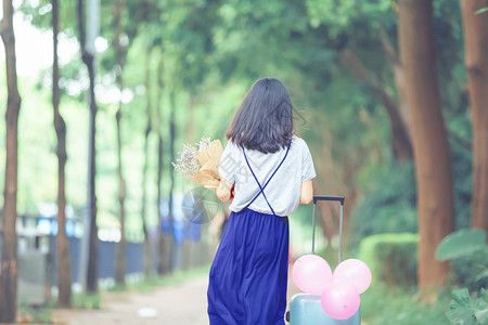粉色桃心气球抱花女孩的走动的飘逸背影背景