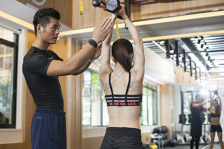 男教练在健身房给女性练习力量背景图片