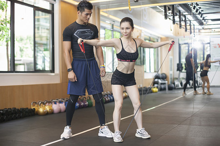 男教练在健身房给女性练习拉伸肌肉图片