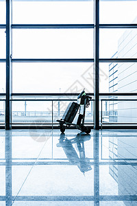 机场明亮落地窗前的旅行箱背景图片