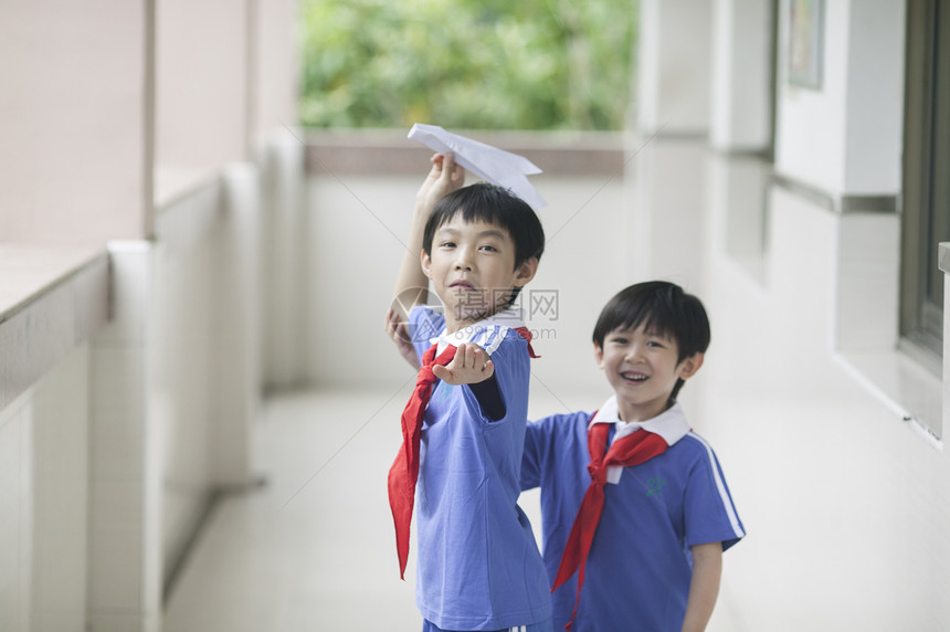 男学生在学校里折飞机玩耍图片