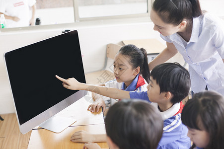 应用电子女老师和同学们在教室里用电脑上课背景