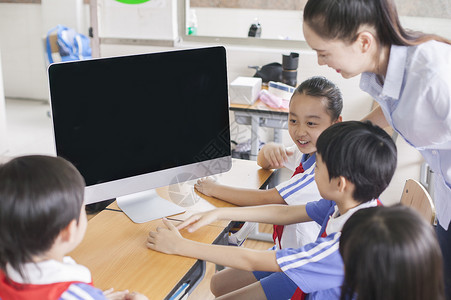 应用电子女老师和同学们在教室里用电脑上课背景