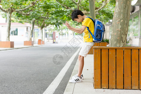 校园林荫道坐着等待家长的小学生图片