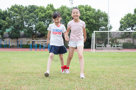 二人三足小学生在操场草坪运动玩游戏背景
