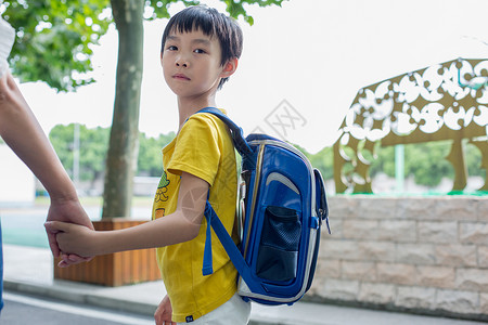 坐着等待牵着妈妈的手去上课的小学生背景