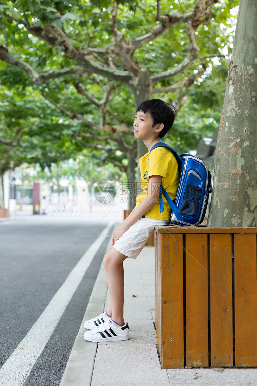 校园林荫道坐着等待家长的小学生图片