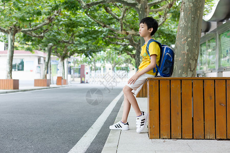 校园林荫道坐着等待家长的小学生背景