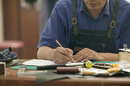 手工画皮匠师傅在专注画皮具草稿背景