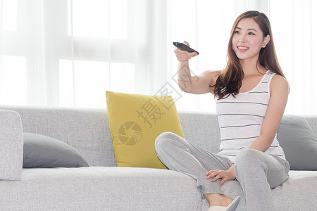 年轻女性在沙发上使用遥控器高清图片