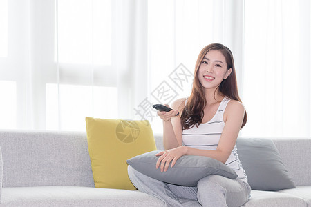 年轻女性在沙发上使用遥控器高清图片