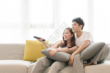 温馨爱情情侣在客厅沙发放松休闲看电视背景
