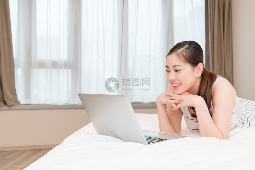 美女趴在床上玩电脑图片