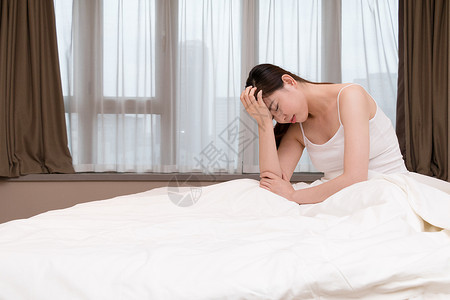 头晕年轻女性失眠头痛坐在床上背景
