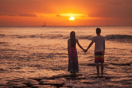小夫妻旅行中浪漫情侣在海中看夕阳背景