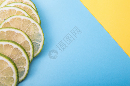 切开的柠檬片柠檬切片蓝色加黄色背景的桌面摆拍背景