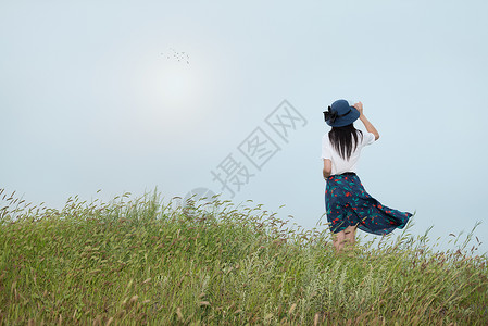 蓝裙子女孩站在草地上的美女背影背景