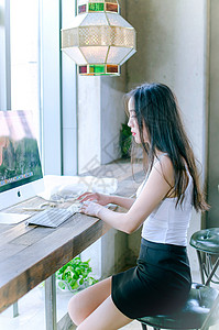 窗边玩电脑的年轻女性图片