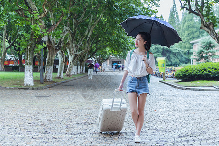 女孩拉着旅行箱下雨天女生拉旅行箱张望背景