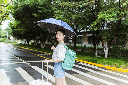 下雨天女生拉旅行箱回头背景图片