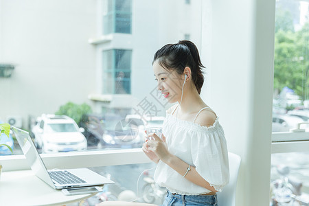 咖啡馆女生手拿水看电脑学习高清图片