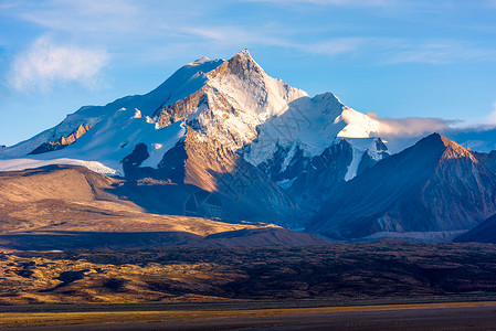 过雪山草地夕阳下的卓木拉日峰背景