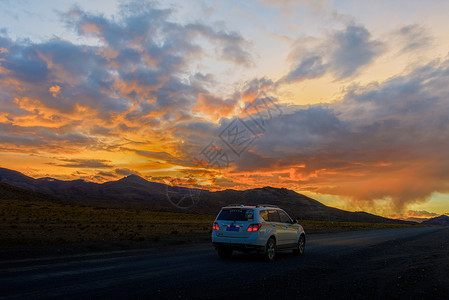崎岖道路夕阳下行驶在公路上的汽车背景