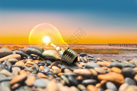 黄昏的海边海边石头堆上发光的灯泡背景