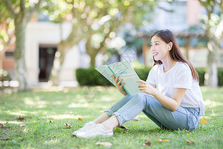 坐在校园草坪上看书的女学生图片素材