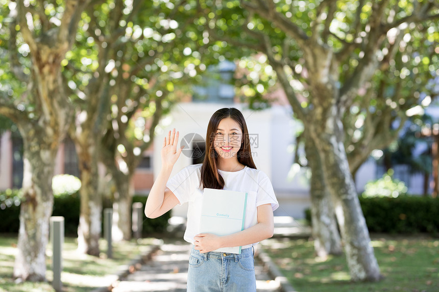 校园里拿着书微笑打招呼的女生图片