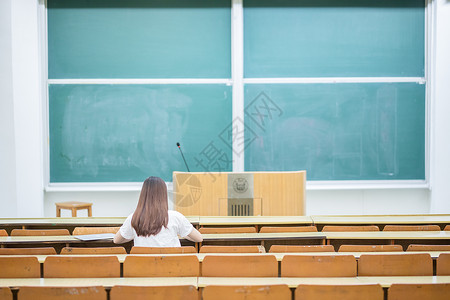 女学生展示黑板空旷的教室里正在学习的女生背影背景