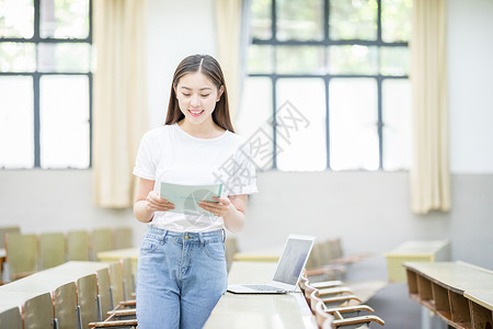 翻开书正在教室自习学习看书的学生背景