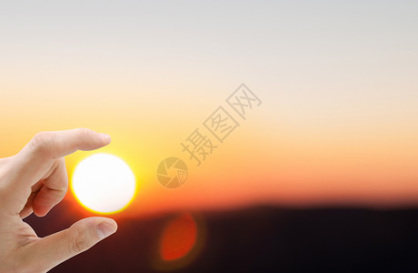 指缝手指间中的夕阳设计图片