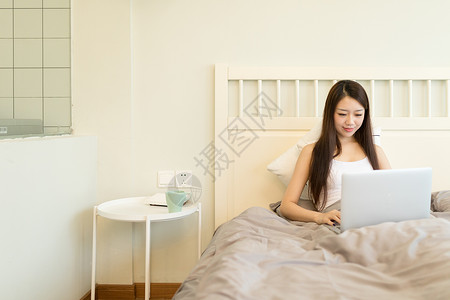 躺在床上玩电脑的年轻女性高清图片