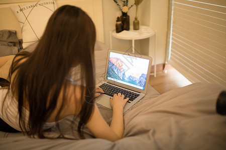 躺在床上玩电脑的年轻女性高清图片