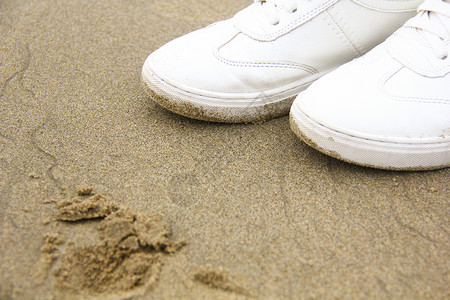 沙滩上的白色球鞋背景图片
