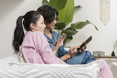 沙发上休息男女情侣在客厅休息玩手机平板电脑背景