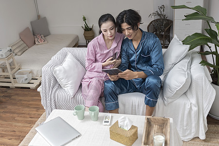 沙发上休息男女情侣在客厅休息玩手机平板电脑背景
