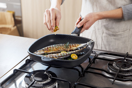 烹饪美食往秋刀鱼上挤柠檬汁烹饪的手高清图片素材