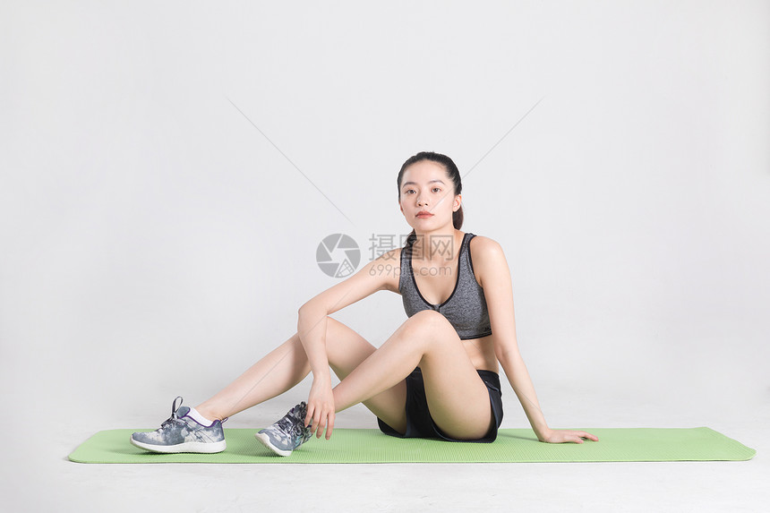 坐在瑜伽垫上休息的年轻女子图片