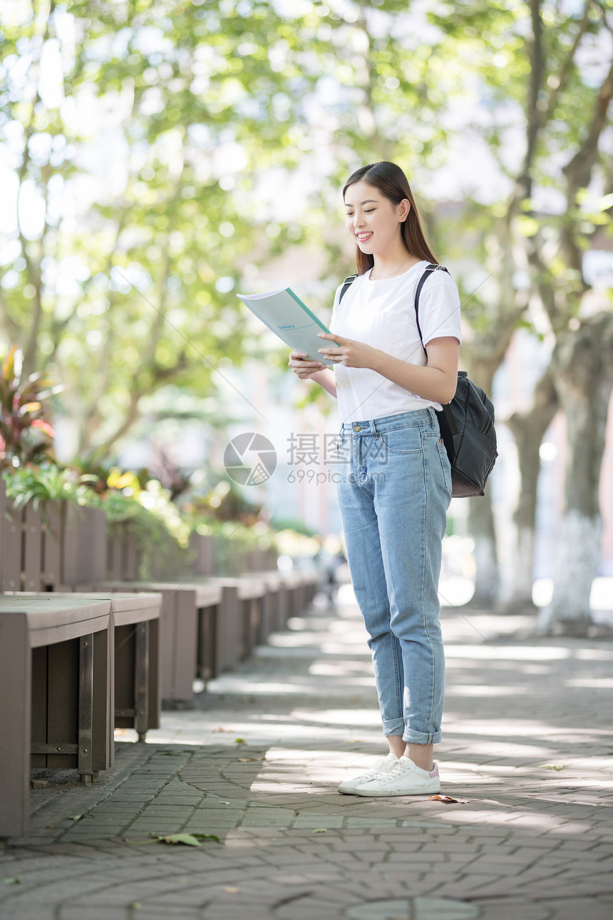 校园里背着书包拿着书的同学图片