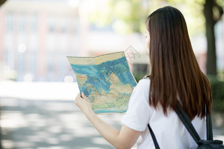 校园地图拿着地图正在找路的年轻女性背景