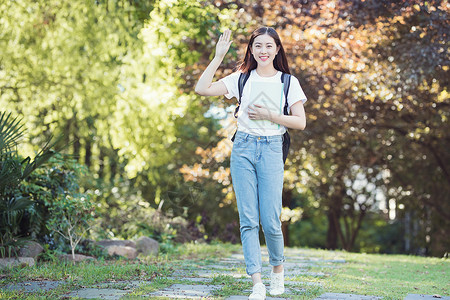 抱着书微笑招手打招呼的女性图片素材