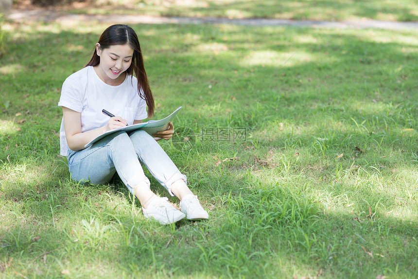 坐在校园草坪上看书学习的同学图片